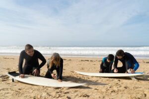 Family prepares surfboards on a sunny beach in Portugal for a fun day of surfing.