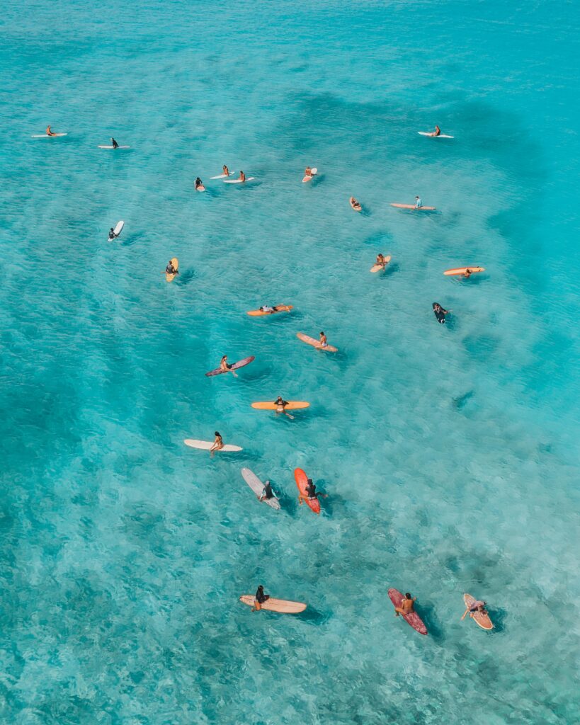 Stunning drone shot of surfers waiting for waves in the clear waters of Hawaii.