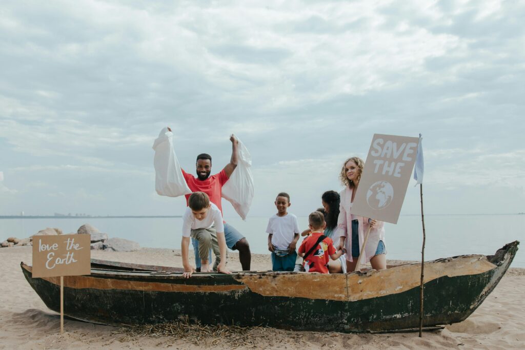 Group of people cleaning beach to promote Earth conservation with signs.